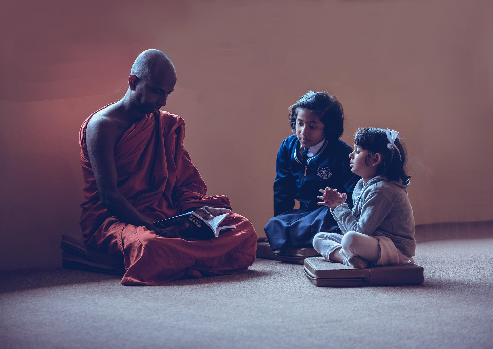 Two children sit with a monk, leaning about mindfulness & meditation
